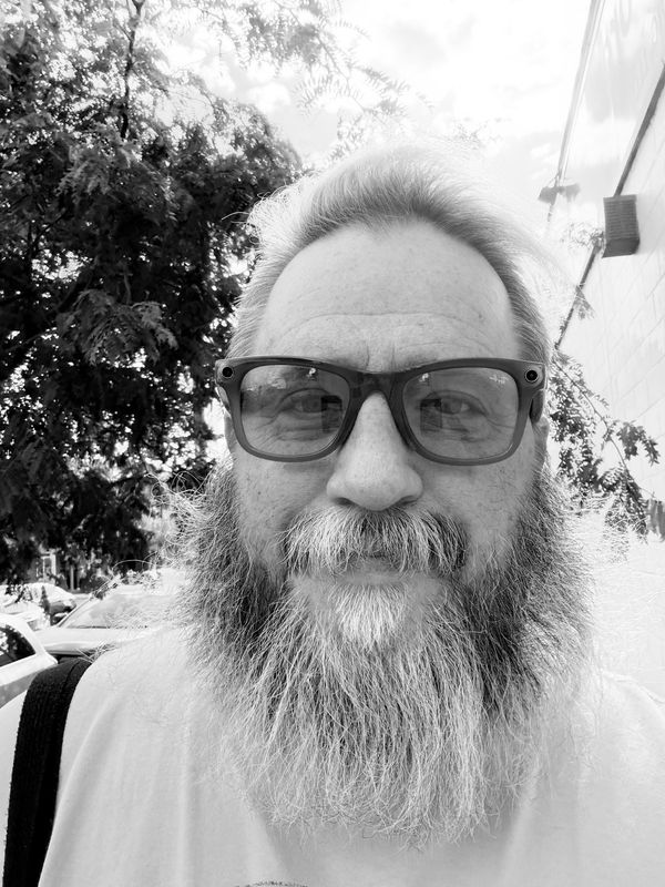 Jason, founder of New To Olde Kensington, a bearded man in glasses on a city sidewalk